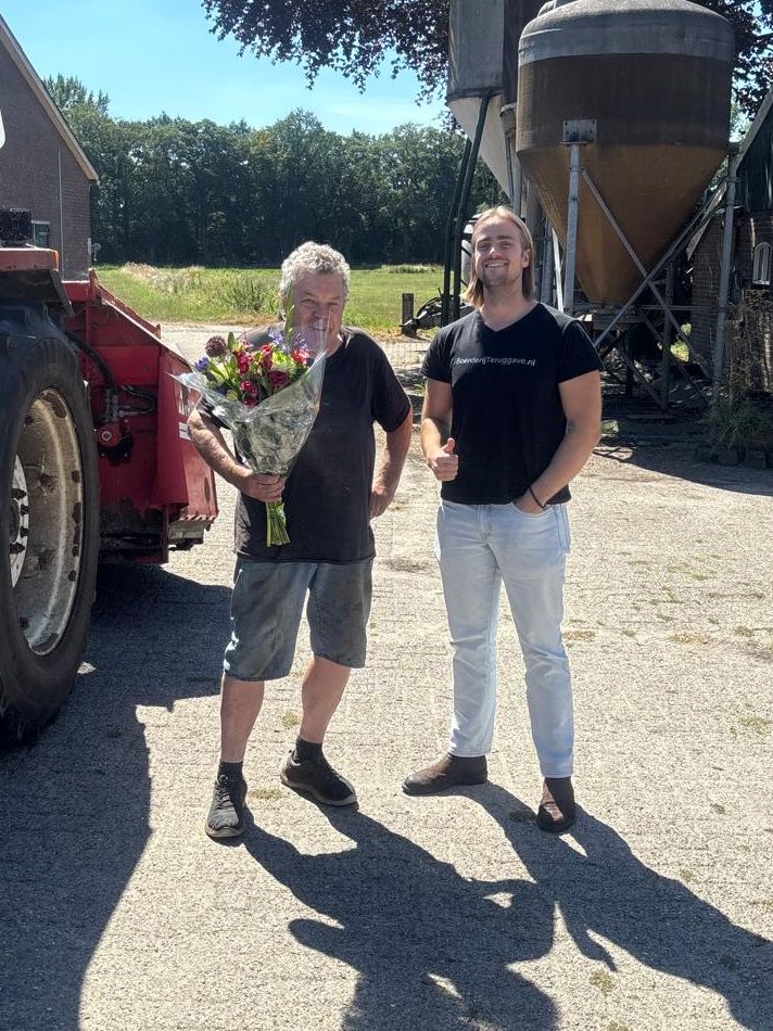 Agrari&euml;r met bloemen naast zijn tractor